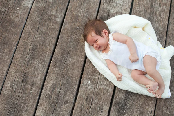 Bambino sdraiato sulla coperta sul pavimento in legno — Foto Stock