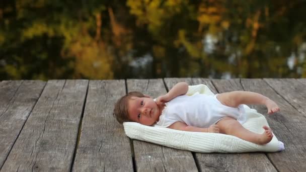 Baby liggend op de deken aan het meer — Stockvideo