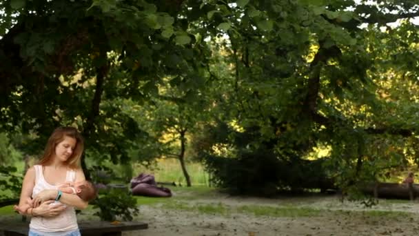 Mère berçant son bébé dans le parc — Video