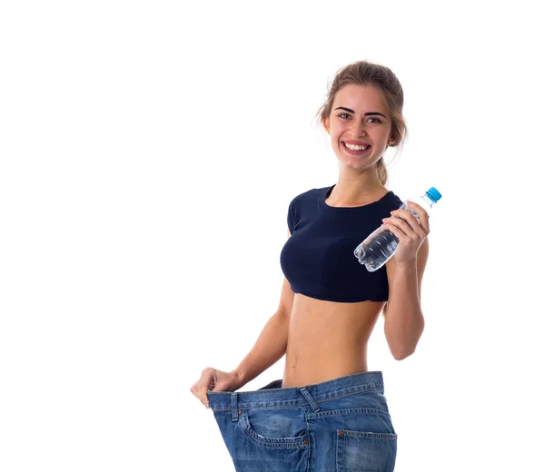 Frau trägt Jeans von viel größerer Größe und hält eine Flasche — Stockfoto