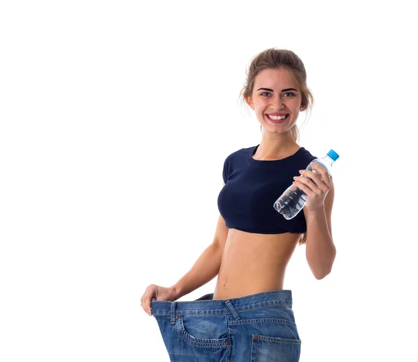 Woman wearing jeans of much bigger size and holding a bottle of — 스톡 사진