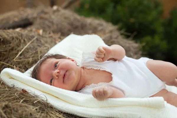 Bebê deitado no cobertor no feno — Fotografia de Stock