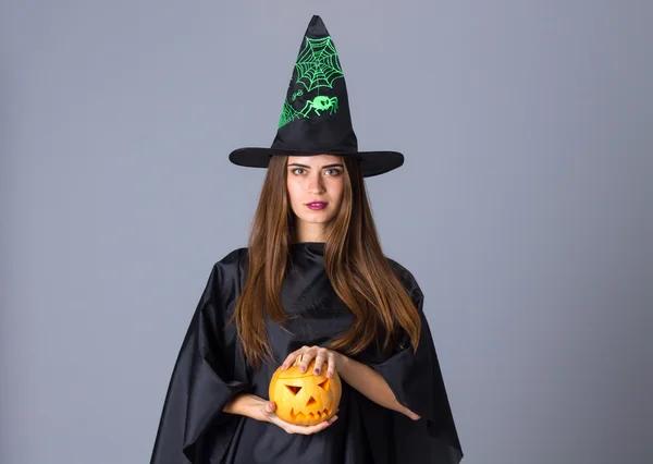 Vrouw in kostuum van heks houden een pompoen — Stockfoto