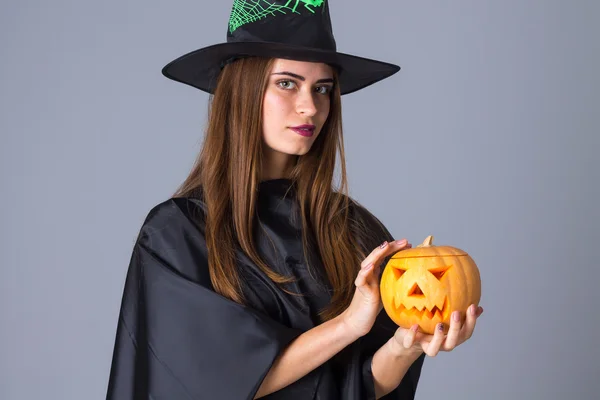 Vrouw in kostuum van heks houden een pompoen — Stockfoto