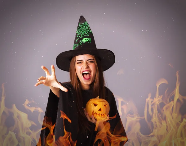 Женщина в костюме ведьмы, держащая тыкву в огне — стоковое фото