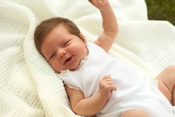 Bebê sorrindo no cobertor na grama — Fotografia de Stock