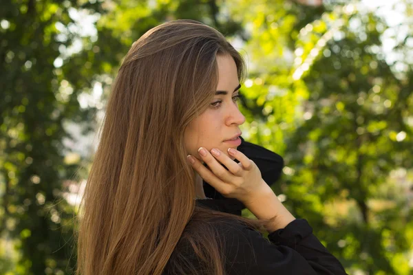 Jonge vrouw permanent terug op de achtergrond van bomen — Stockfoto