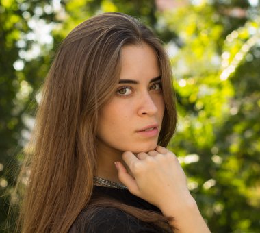 Sidewise ağaçlar arka plan üzerinde duran genç kadın