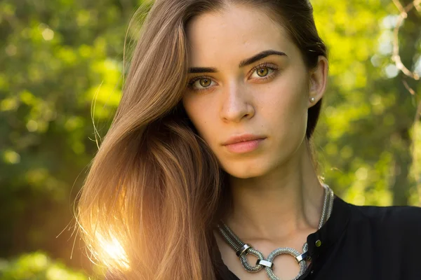 Jonge vrouw op de achtergrond van bomen — Stockfoto