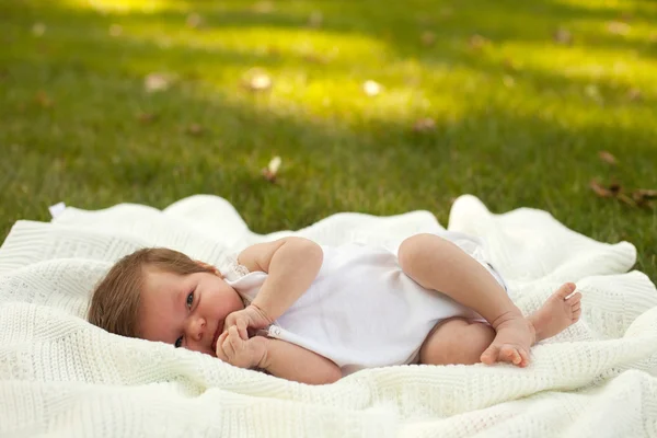 Bébé couché sur la couverture sur l'herbe — Photo