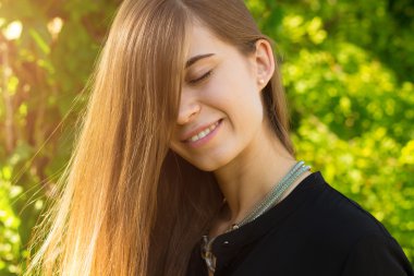 Young woman closing eyes on the background of trees