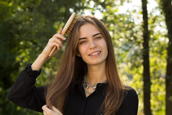 Vrouw kammen van haar haren in het park — Stockfoto