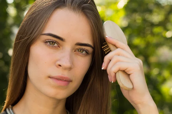 Vrouw kammen van haar haren in het park — Stockfoto