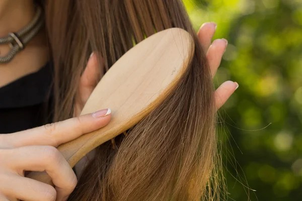 Woman combing her hair in the park — Stock Photo, Image