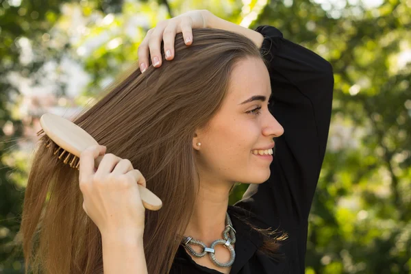 Donna pettinarsi i capelli nel parco — Foto Stock