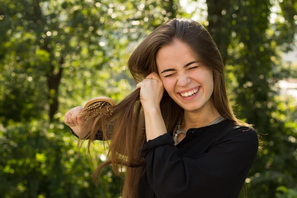 Vrouw kammen van haar haren in het park — Stockfoto