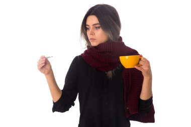 Woman holding a cup and looking at thermometer