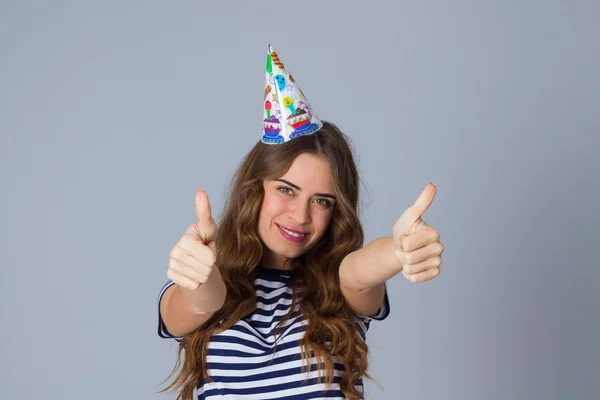 Woman in celebration cap showing thumbs up — Stock fotografie