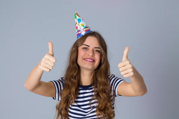 Woman in celebration cap showing thumbs up — Stockfoto