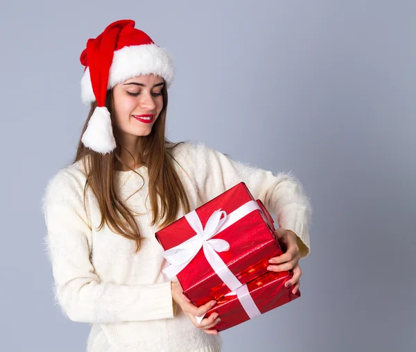 Kvinna i röd jul hatt hålla presenterar — Stockfoto