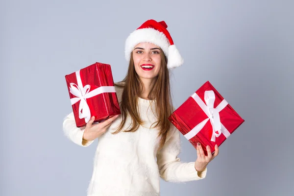 Woman in red christmas hat holding presents — Stock Photo, Image