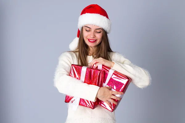 Kvinna i röd jul hatt hålla presenterar — Stockfoto
