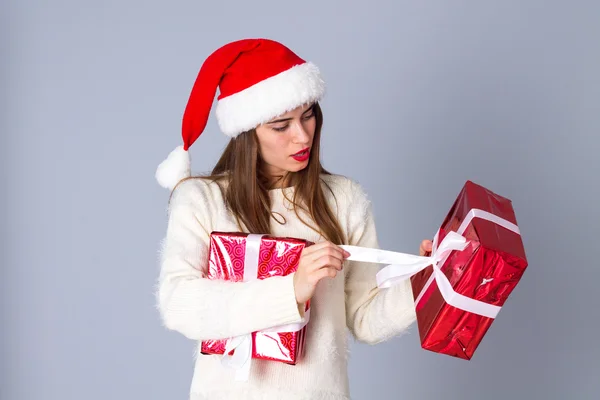 Kvinna i röd jul hatt öppning presenterar — Stockfoto