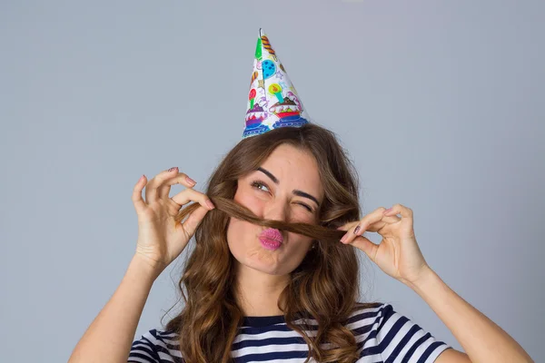 Woman in celebration cap making moustache of her hair — ストック写真