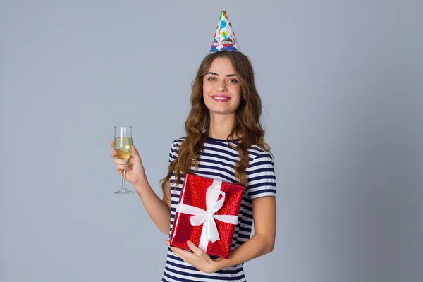 Mujer en gorra celebración sosteniendo un regalo y un vaso — Foto de Stock