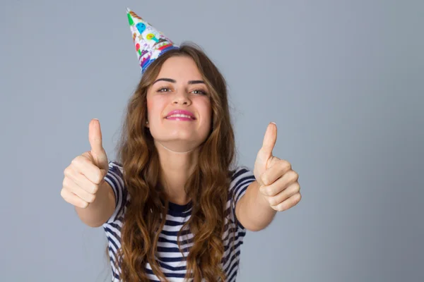 Woman in celebration cap showing thumbs up — Stock fotografie