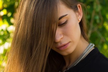 Ağaçların arkasına bakan genç bir kadın.