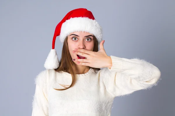 Woman in red christmas hat hiding her mouth — Stock Photo, Image