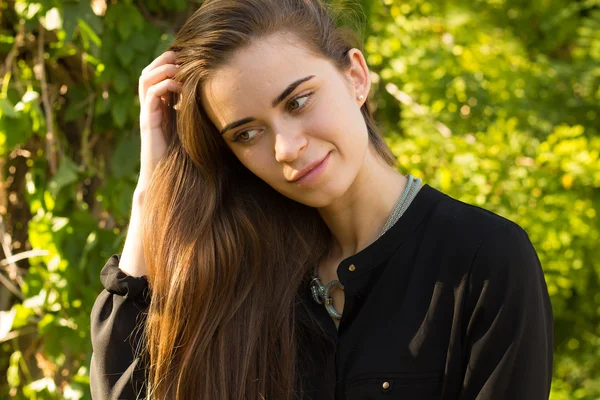 Jonge vrouw op de achtergrond van bomen — Stockfoto