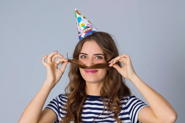 Woman in celebration cap making moustache of her hair — Φωτογραφία Αρχείου