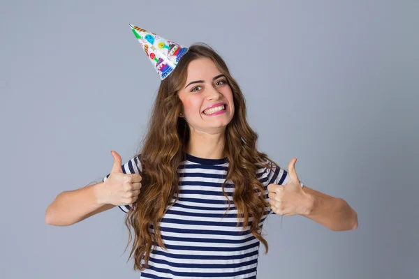Woman in celebration cap showing thumbs up — Stockfoto