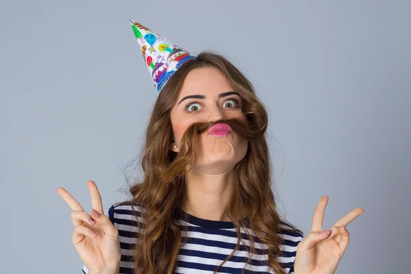 Woman in celebration cap making moustache of her hair — Stock Photo, Image