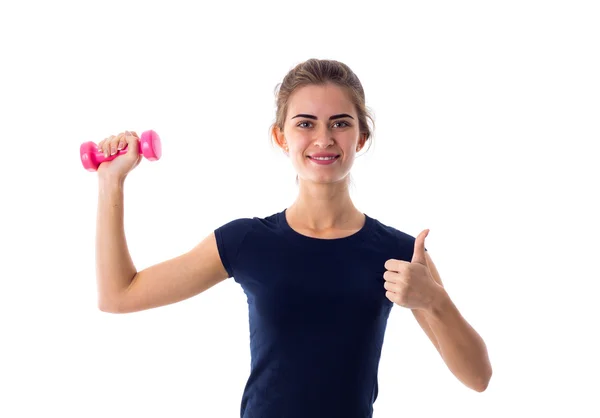 Woman holding a dumbbell and showing thumb up — Stock fotografie