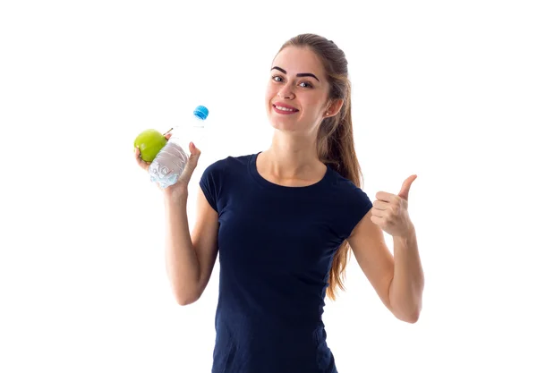 Женщина держит яблоко и воду и показывает большой палец вверх — стоковое фото