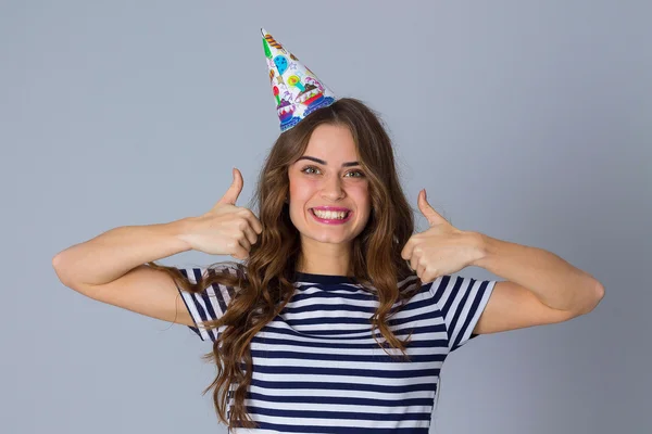 Woman in celebration cap showing thumbs up — Stockfoto