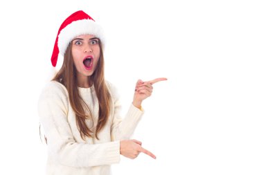 Bir şeye işaret eden kırmızı Noel şapkalı kadın