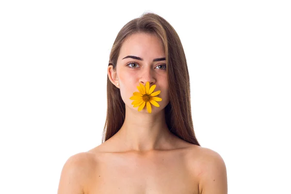 Νεαρή γυναίκα κρατώντας κίτρινο λουλούδι στα χείλη — Φωτογραφία Αρχείου
