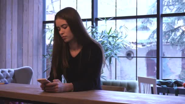 Mujer joven en la cafetería con teléfono móvil — Vídeos de Stock