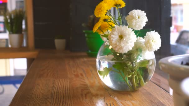 Όμορφα λουλούδια σε ένα γυάλινο βάζο σε ένα τραπέζι — Αρχείο Βίντεο