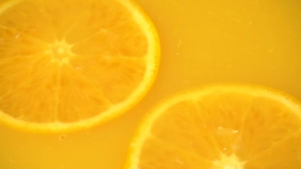 Naranja en rodajas cayendo en jugo de naranja — Vídeo de stock