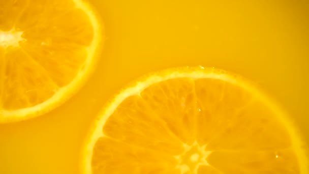Нарезанный апельсин падает в апельсиновый сок — стоковое видео