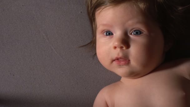 Schattig klein meisje liggend op bed en in de camera kijken — Stockvideo