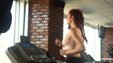 Spor salonunda treadmill çalıştıran çekici beyaz kız