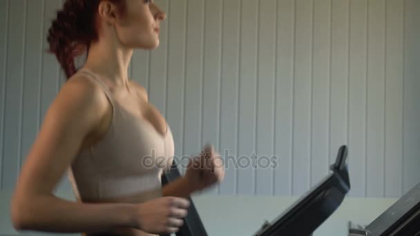Mujer atractiva corriendo en la cinta de correr en el gimnasio deportivo — Vídeos de Stock