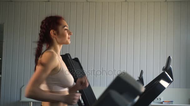 Menina caucasiana atraente correndo na esteira no ginásio esporte — Vídeo de Stock