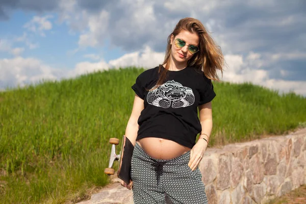 Pregnant woman holding a skateboard — Stock Photo, Image